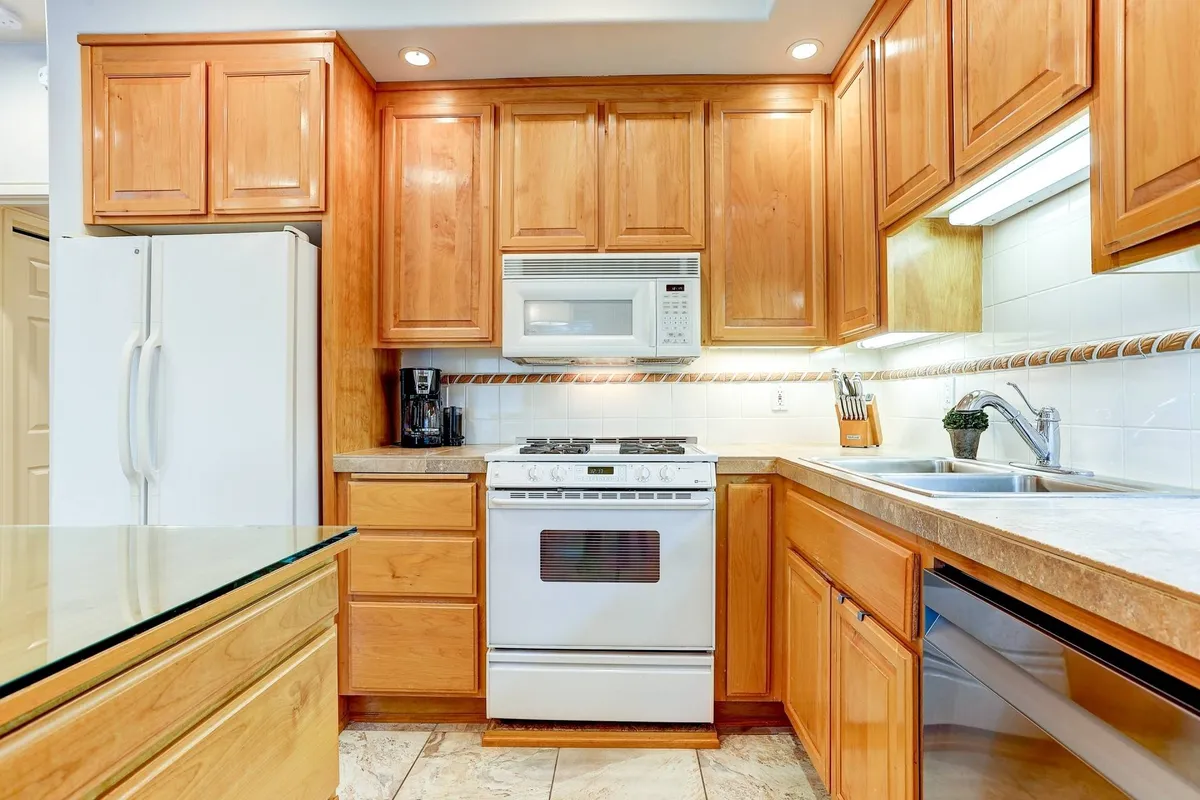 This image captures a welcoming kitchen featuring wooden cabinetry, stainless steel appliances, and a spacious countertop with a sink. The space is well-lit and exudes warmth and hospitality, suggesting a place where guests can gather, prepare meals, and enjoy time together after outdoor adventures.