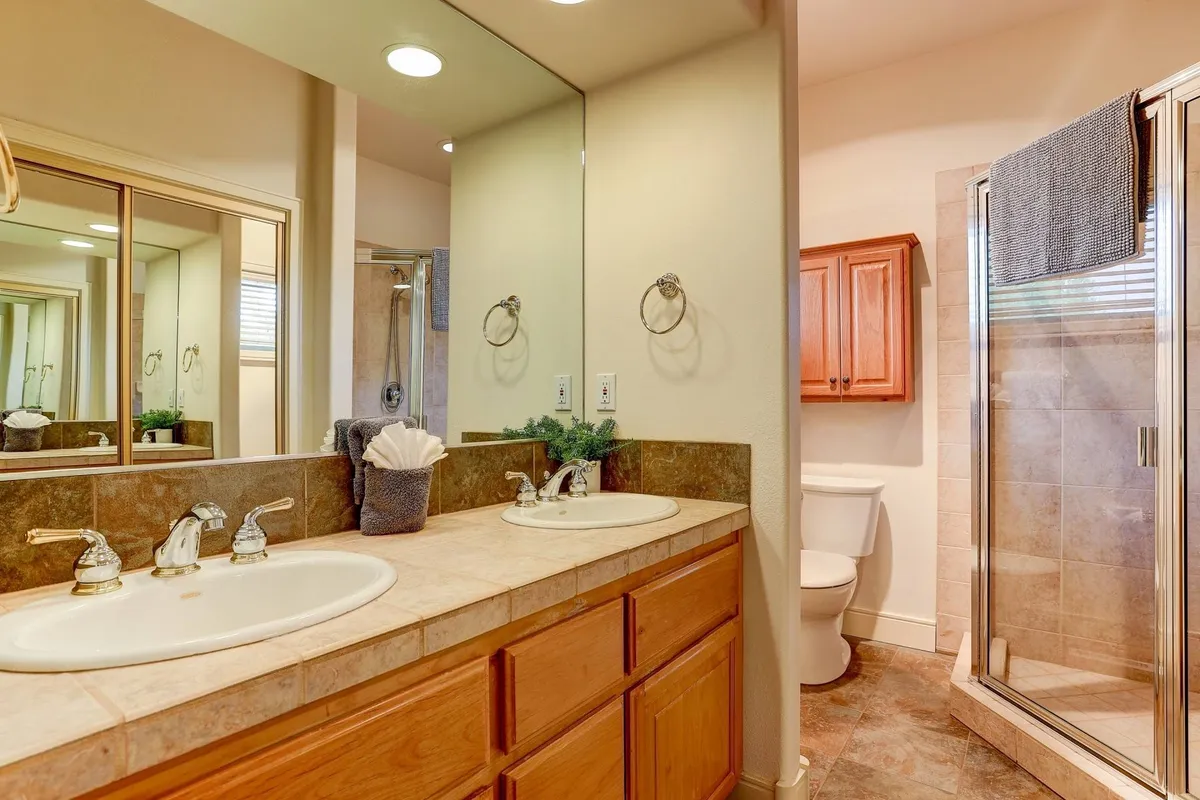 A stylish bathroom with a double vanity sink, large mirror, and a modern shower stall, exuding a tranquil and organized atmosphere ideal for relaxation and self-care.