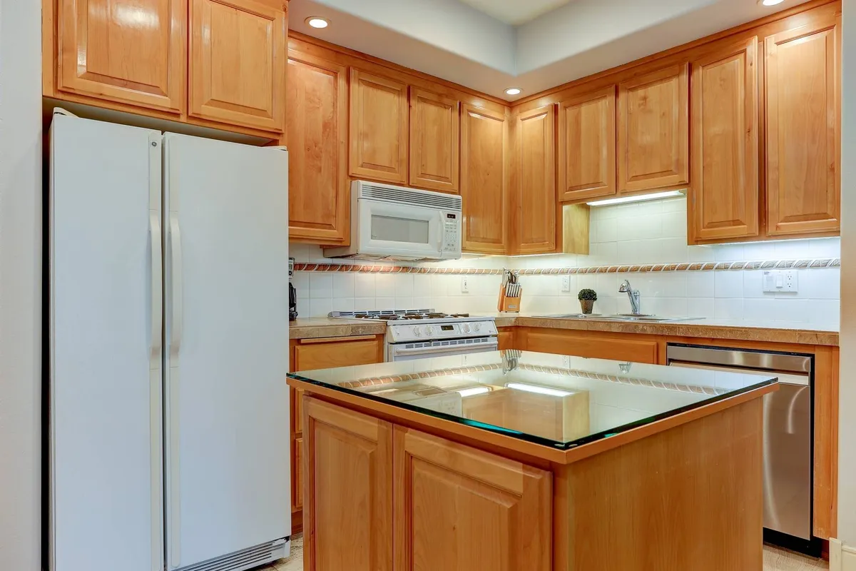 This kitchen image highlights a spacious island, gleaming stainless steel appliances, and wooden cabinetry. The layout suggests a sociable space for meal preparation and gathering, with plenty of room for multiple cooks or guests to mingle.